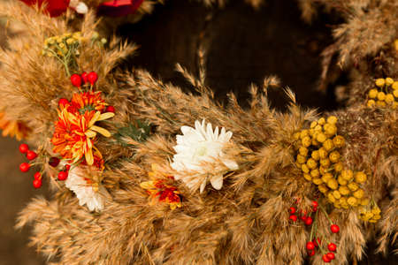 Making wreath autumn colorful leaves and natural materials on rustic wooden boards. Top view of round wreath autumn harvest and foliage on brown wood. Decoration for interior.の写真素材