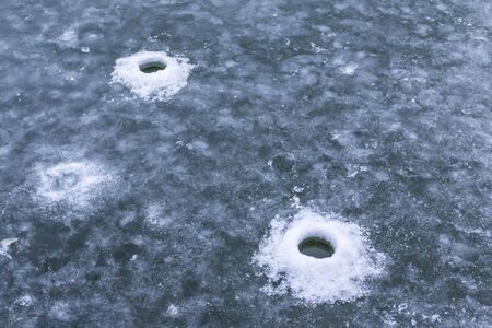 The wells in the ice to catch fish. Ice Fishing in Warsaw, Poland.の写真素材