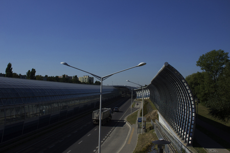 Bus stop near the sound-absorbing tunnel. Metal structure and screens, glass. Modern technology in the city of Warsaw, Poland.	の写真素材