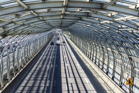 Cars on the road in the sound-absorbing tunnel. Metal structure and glass. Modern technology in the city of Warsaw, Poland.	の写真素材
