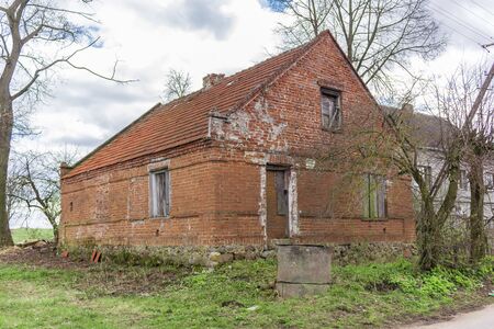 Abandoned brick apartment house in the village. Village Street in mid-April. Region Podlasie, Poland.の写真素材