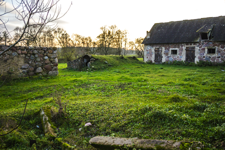 The farmyard is an agricultural abandoned farm. The old collapsed barns. The entrance to the cellar is like a cave. The late autumm . Podlasie, Poland.の写真素材