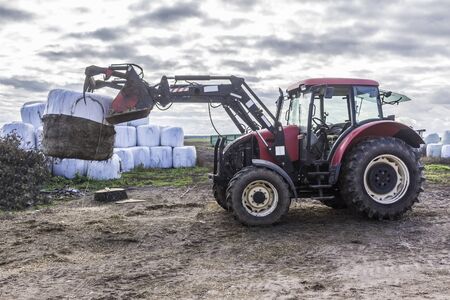 Wheel tractor with a lift for carrying bales with a silo. Daily work at a dairy farm. Podlasie,...