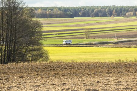 Late autumn. Brown arable land and yellow field.  Forest and fields separated by boundary furrows in the background . Dairy farm . Podlasie, Poland.の写真素材