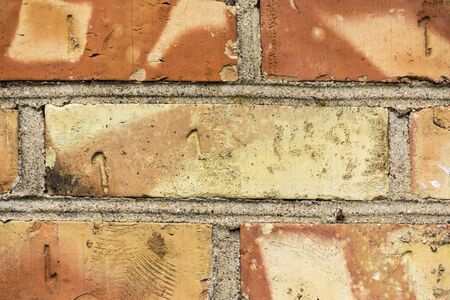 Wall of clay red-yellow bricks. On the motley sides, the number thirteen and one is extruded.Site...