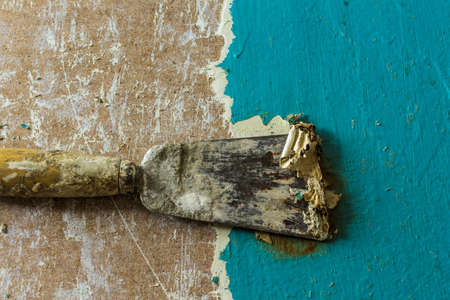 Restoration of an old door.Removing old paint coats with a heat gun and a spatula.View from above .Close up. The spatula removes the blue paint layer.の写真素材