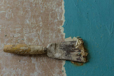 Restoration of an old door. Removing old paint coats with a heat gun and a spatula. View from above. The spatula removes the blue paint layer.の写真素材
