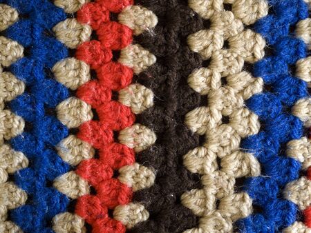 synthetic woollen knitted crochet rug closeup texture red white blue brown background