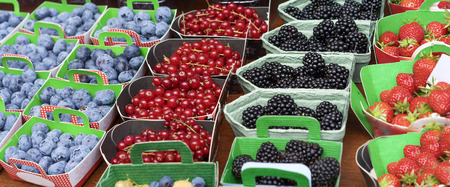Baskets of Fresh Berries at Fruit Market with natural ripe colorful nutritious blackberries strawberries and blueberriesの写真素材
