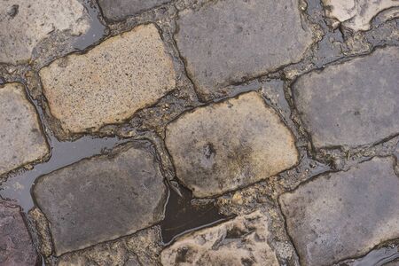 Water puddles from rain on wet cobblestone roadの写真素材
