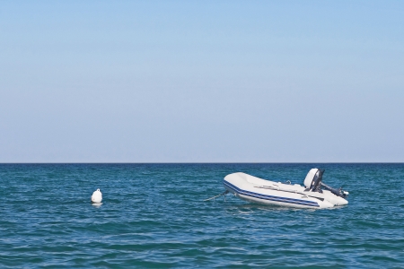 Anchored dinghy on sea with blue sky の写真素材