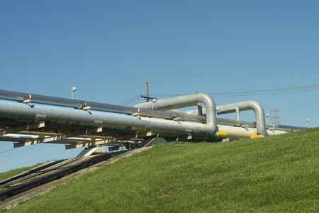 Pipes from an oil refinery transport chemicals over a levee on the Mississippi river.
