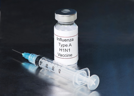 H1N1 Influenza vaccine and syringe on metallic background.の写真素材