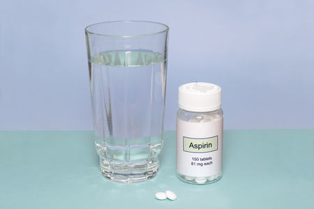 Aspirin bottle with glass of water.の写真素材
