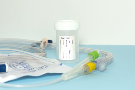 Urine sample container with foley catheter on blue.の写真素材