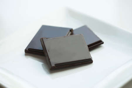 Dark chocolate squares on white serving dish.の写真素材