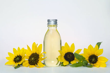 Sunflower oil bottle and sunflowers on light cream background.の写真素材