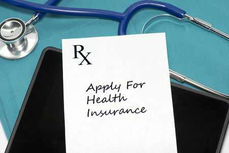 Prescription to apply for health insurance with personal computing device and stethoscope on scrubs.の写真素材