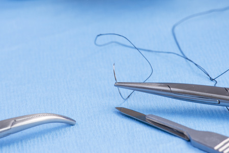 Needle holder with silk suture on blue sterile drape.の写真素材