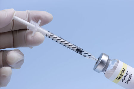 Nurse injects air into regular insulin vial prior to drawing medication.の写真素材