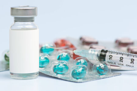 Vial with blank label, syringe and blister packs of medication.