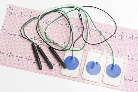 Electrocardiogram leads and electrocardiograph on white tabletop.の写真素材