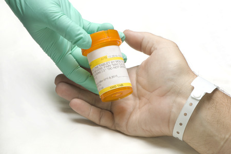 Nurse gives prescription medication to hospital patient.の写真素材