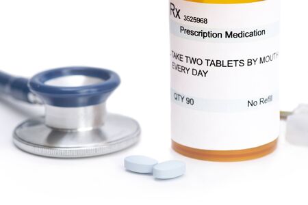 Prescription bottle with pills and stethoscope on white. Label and all information contained therein is fictitious.の写真素材