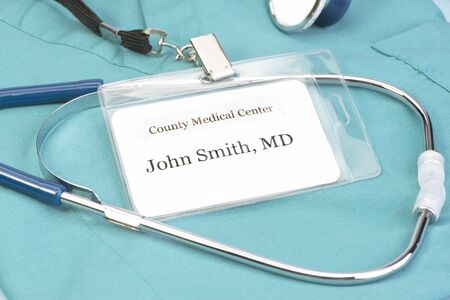 Obviously fictitious Doctor identification tag on scrubs with stethoscope.の写真素材