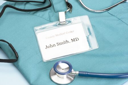 Obviously fictitious Doctor identification tag on scrubs with stethoscope.の写真素材