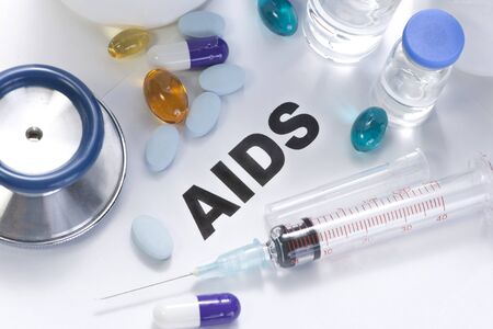 AIDS concept photo with stethoscope, pills, syringe and vials.