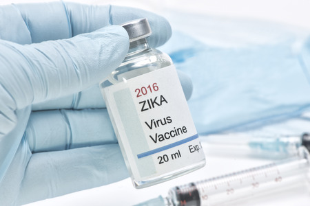 Hypothetical Zika virus vaccine held by health care worker gloved hand. Label is fictitious and created by photographer.の写真素材