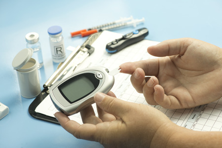 Blood sugar finger stick test with glucometer and diabetic supplies.の写真素材