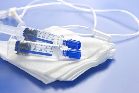 Heparin lock flush syringes on sterile gauze with IV tubing.の写真素材