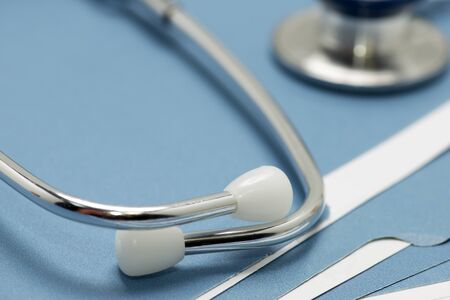 Stethescope on blue folders containing patiient medical charts.