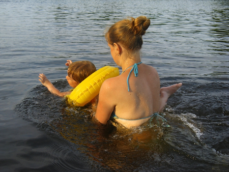 Mom and little baby daughter on the river are trained to swim with the help of an inflatable circle....