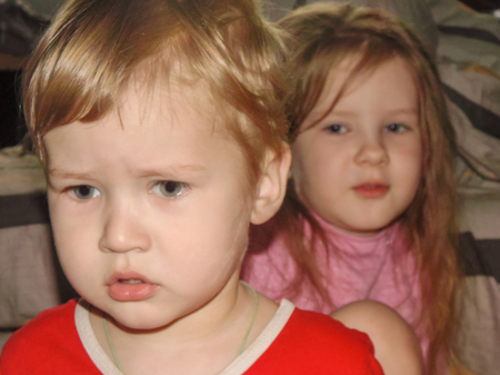 Little serious little kids brother and sister are sitting at a loss. Children endure punishment...