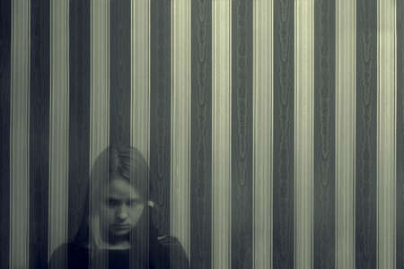 A young translucent ghost girl looks directly at the viewer with a reproach on the background of a...