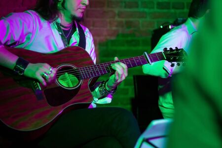 Guitarists on stage in the spotlight. Young music band in a night club. Music for the soul.の写真素材