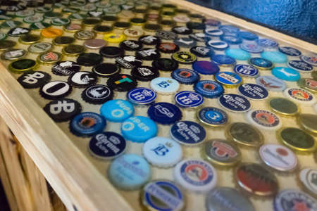 Minsk, Belarus - June 15, 2019: Original surface of the countertop is created from decorative elements and epoxy. Collection of beer caps with different brands of beer is collected at the bar.のeditorial素材