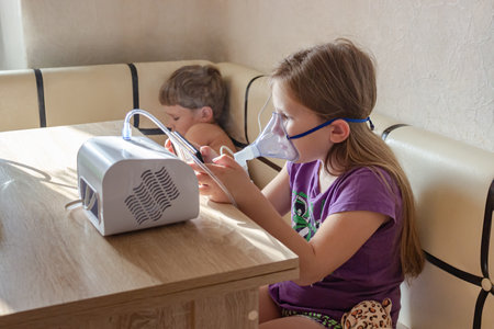 Two small children take turns taking inhalation for a sore throat at home