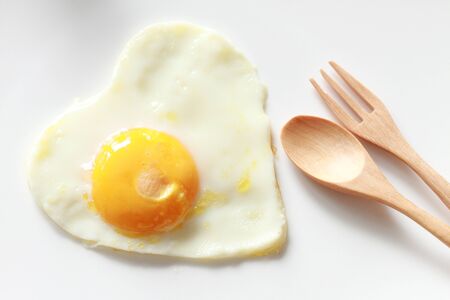 heart-shaped fried egg with spoon and forkの写真素材