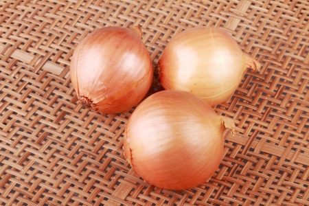 three onions on wooden basketryの写真素材