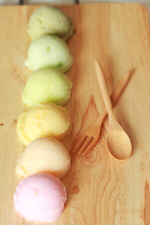six colorful ice cream scoops in a row with spoon and forkの写真素材