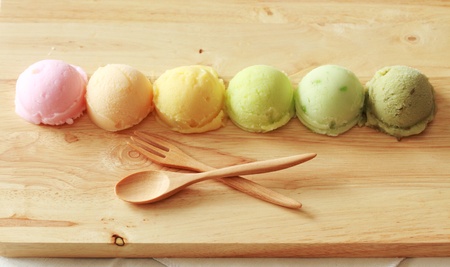six colorful ice cream scoops in a row with spoon and forkの写真素材