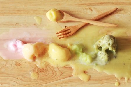melting colorful ice cream scoops in a row with spoon and forkの写真素材