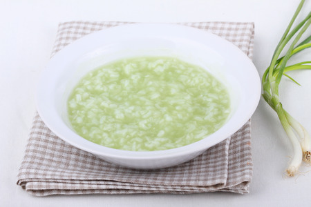 Rice pudding  in an individual bowl  with spring onion on white backgroundの写真素材
