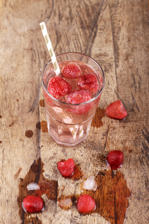 strawberry soda drinks and melted ice cube  on wood table backgroundの写真素材