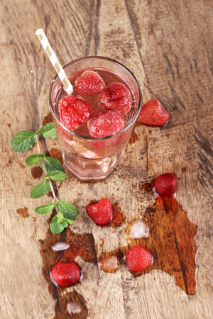 strawberry soda drinks and melted ice cube  on wood table backgroundの写真素材