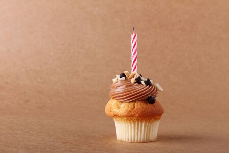 birthday cupcake with candle on plain backgroundの写真素材
